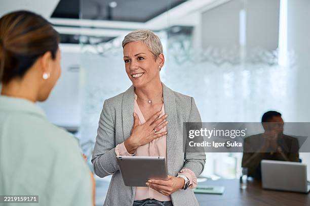 grateful businesswoman holding tablet and talking with colleague in the office - showing empathy stock pictures, royalty-free photos & images