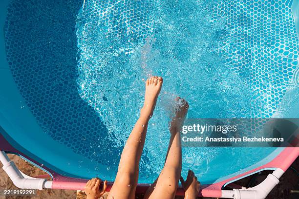 child splashing feet in pool on summer day - gartenpool stock-fotos und bilder