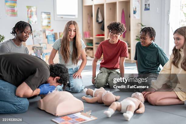 teenagers learning cpr techniques in a lifeguard and babysitting training course - teen cpr stock pictures, royalty-free photos & images