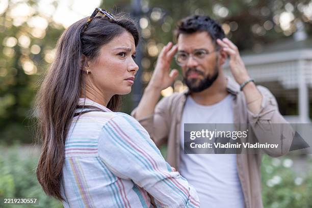 una mujer observa al hombre en el fondo durante una acalorada discusión al aire libre - confrontación fotografías e imágenes de stock