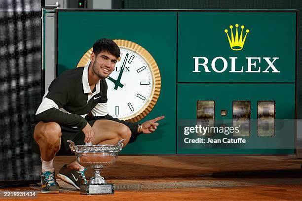Winner Carlos Alcaraz of Spain poses next to the Rolex clock after the longest men's final in Roland-Garros on day 15 of the 2025 French Open,...