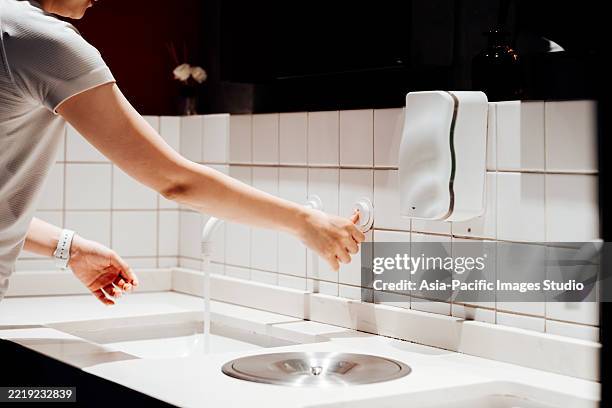 cropped shot of young asian woman washing her hands before smart mirror at bathroom while she traveling. maintaining hands hygiene. keeps the germs away and preventing contagious disease. - soap dispenser stock pictures, royalty-free photos & images