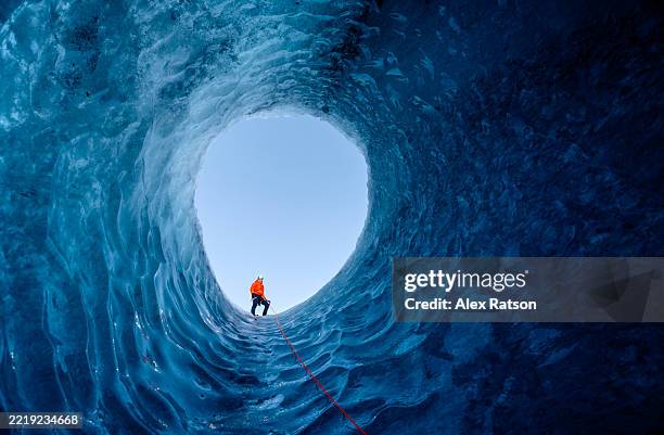 stunning glacial ice cave: an ice climber looks down into the depths - vatnajokull photos et images de collection