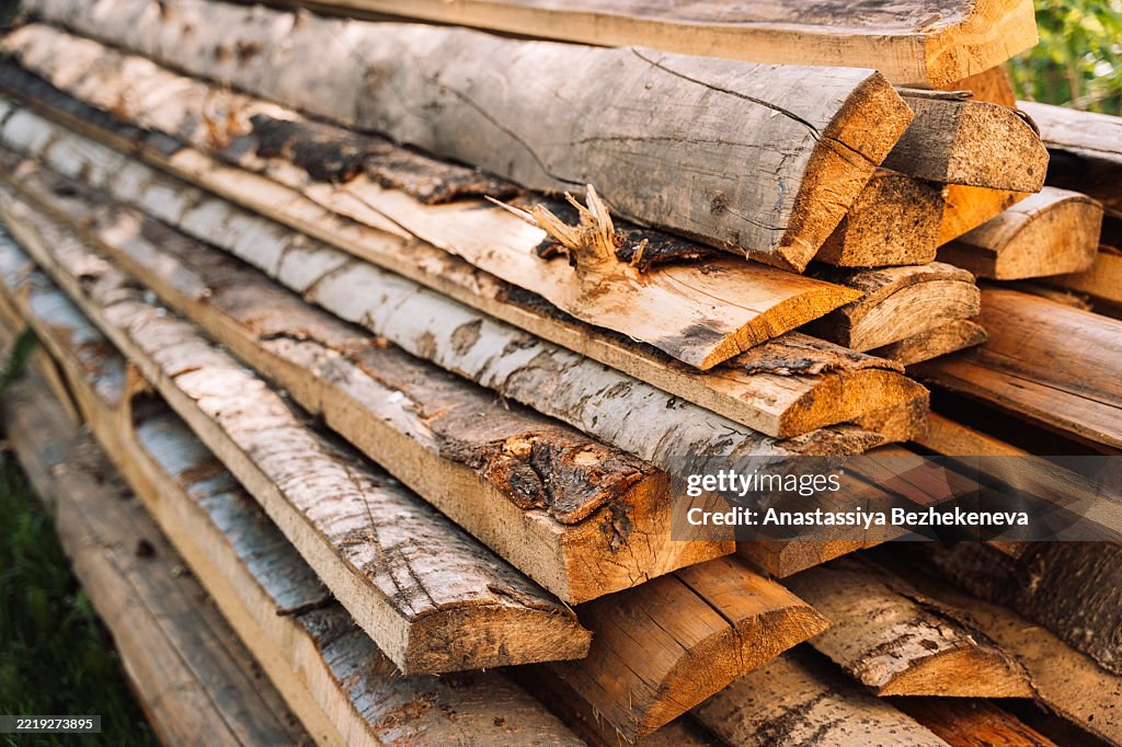 Stack of split firewood neatly arranged in an outdoor pile. A close-up view of natural textures and warm wood tones