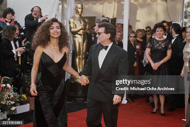 American actress Claudia Haro, wearing a black evening gown, and her husband, American actor Joe Pesci, who wears a tuxedo, bow tie and sunglasses,...