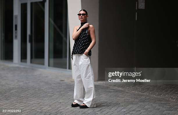 Sophia Geiss is seen wearing silver hoop earrings in two different sizes; narrow oval black sunglasses from Saint Laurent; a silver nose ring; a...