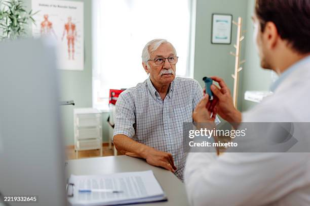 doctor showing senior man how to use asthma inhaler - image technique stock pictures, royalty-free photos & images