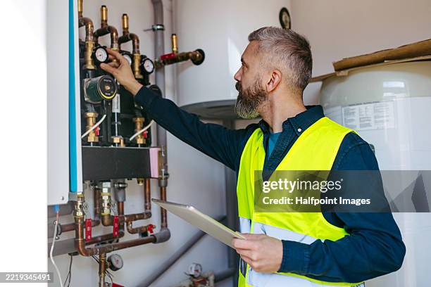 technician inspecting circulation pumps for underfloor heating system. - boiler stockfoto's en -beelden