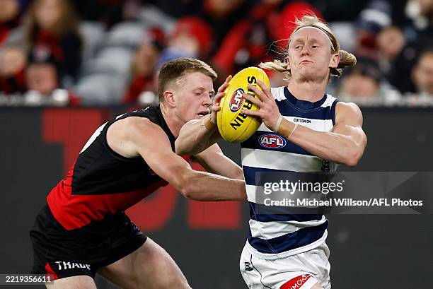 Oliver Dempsey of the Cats evades Angus Clarke of the Bombers during the 2025 AFL Round 14 match between the Essendon Bombers and the Geelong Cats at...