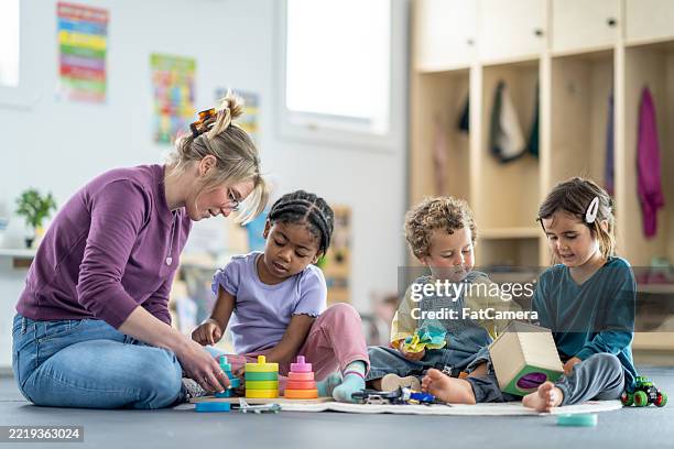 group of children learning with teacher in a preschool environment - kinderopvang stockfoto's en -beelden