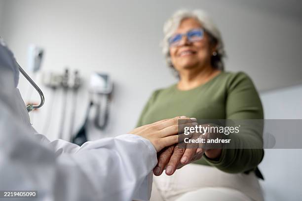 doctor holding the hand of a senior patient at the hospital - annual event stock pictures, royalty-free photos & images
