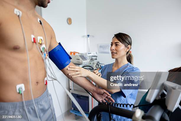 arzt, der den blutdruck eines mannes überprüft, der in einer klinik einen belastungstest durchführt - kardiologe stock-fotos und bilder