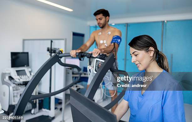 arzt, der die vitalparameter eines mannes während eines belastungstests überwacht - belastungsprobe stock-fotos und bilder