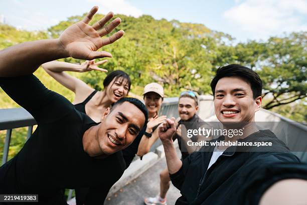 group of energetic runners jogging together in sync while their club leader running alongside them, holding a camera to capture the moment - gym selfie stock pictures, royalty-free photos & images