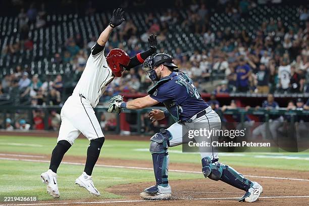 Ildemaro Vargas of the Arizona Diamondbacks is out at home plate ahead of catcher Cal Raleigh of the Seattle Mariners during the 10th inning of the...