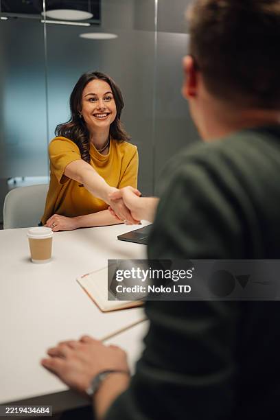 dos jóvenes empresarios se dan la mano después de un exitoso encuentro en la oficina - entrevista de trabajo fotografías e imágenes de stock