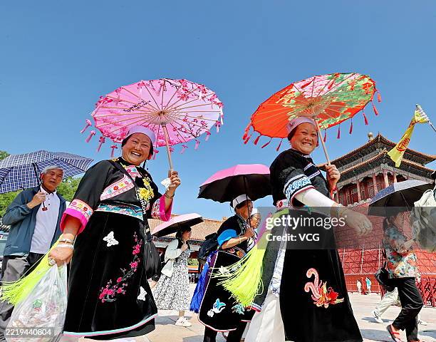 Visitors to the Palace Museum, also known as the Forbidden City, manage to protect themselves from the hot sun with some putting up umbrellas and...