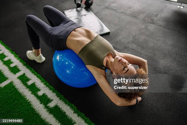 mujer acostada en la pelota de ejercicio estirándose relajadamente - mentalidad fotografías e imágenes de stock