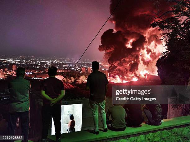 People observe fire and smoke from an Israeli attack on the Shahran oil depot on June 15, 2025 in Tehran, Iran. Iran's foreign minister said the...