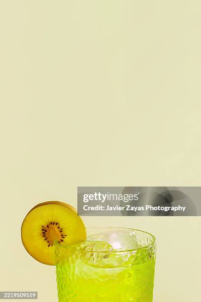 refreshing kiwi cocktail with ice and kiwi slice on light green background - kiwi slice stock pictures, royalty-free photos & images