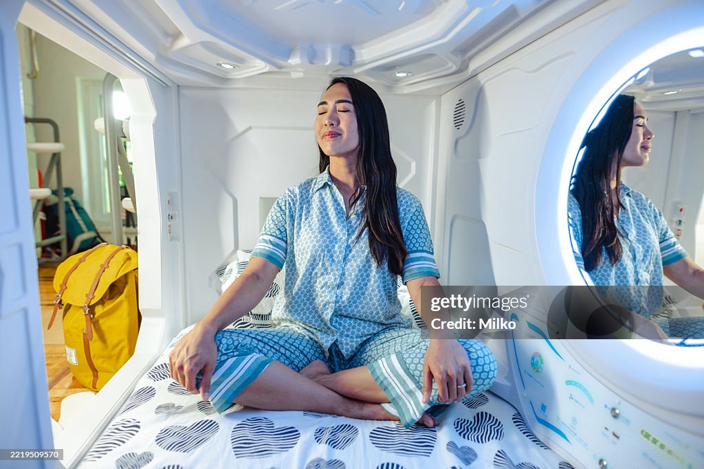 Woman practicing mindfulness seated in a modern capsule hotel unit