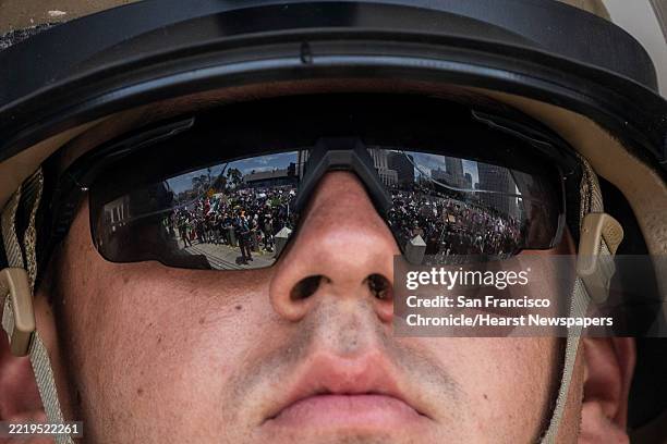 Protesters are seen reflected on the sunglasses of a U.S. Marines from 2nd Battalion, 7th Marines, 1st Marine Division outside the North Los Angeles...