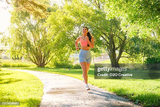 jeune femme faisant de l’exercice dans un parc un matin d’été - joggeuse photos et images de collection