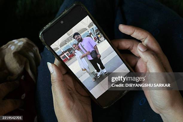 Rinal Christian, sister of Lawrence Christian, a victim of the Air India Flight 171 crash, shows a picture of her late brother hugging their mother...