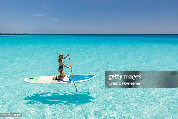 mujer feliz disfrutando mientras rema en un día de verano en el mar. - deporte acuático fotografías e imágenes de stock
