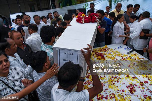 Relatives grieve near the coffin containing the remains of Rozar David Christian, a victim of the Air India plane crash, outside his home in...