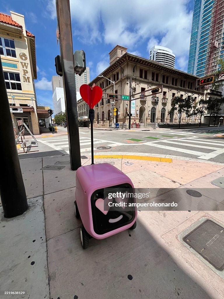 Pink delivery robot waiting on the sidewalk in Miami, Florida