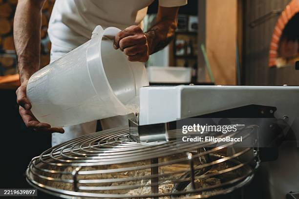 bäcker, der wasser in eine professionelle knetmaschine gießt - teig kneten stock-fotos und bilder