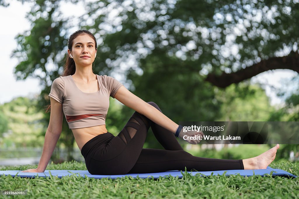 Young woman performing a seated spinal twist in a park