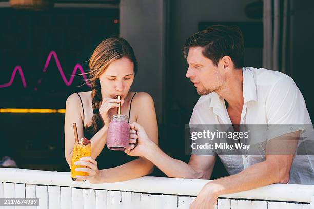 man and woman sharing a fresh cold drinks from mason jar with straws. - stoffwechsel entgiftung stock-fotos und bilder