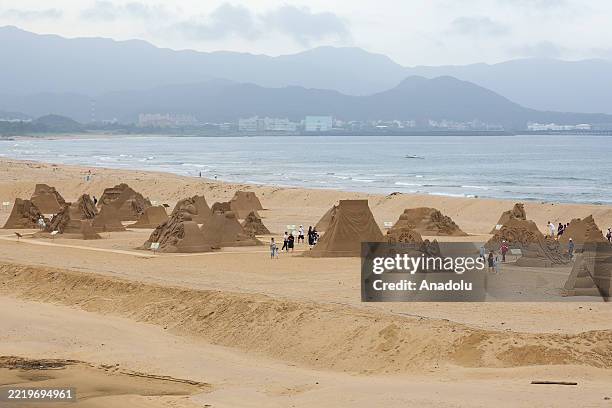 People engage with different cartoon sand sculptures during the Fulong International Sand Sculptures Art Festival, at Fulong beach in New Taipei,...