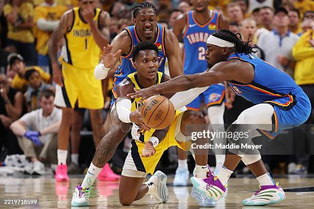Bennedict Mathurin of the Indiana Pacers passes the ball between Jalen Williams and Luguentz Dort of the Oklahoma City Thunder during the fourth...