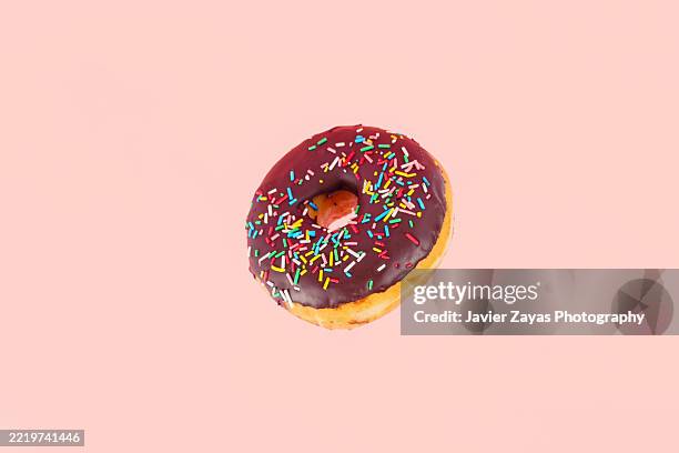 delicious chocolate donut floating on pink background - hundreds and thousands stock pictures, royalty-free photos & images