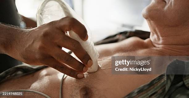 kardiologe, der ein echokardiogramm an der brust eines älteren männlichen patienten durchführt - echokardiogramm stock-fotos und bilder
