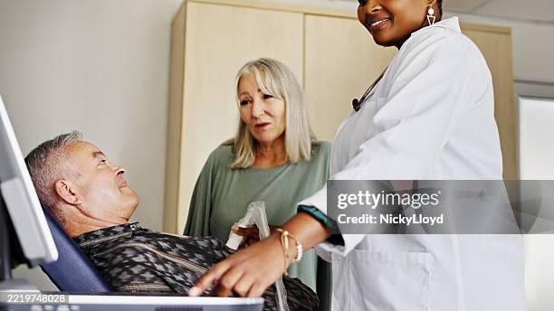 kardiologe zeigt medizinische testergebnisse für älteren patienten und ehefrau in der klinik - echokardiogramm stock-fotos und bilder