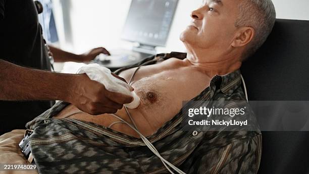 kardiologe führt ein echokardiogramm bei einem älteren männlichen patienten durch - echokardiogramm stock-fotos und bilder
