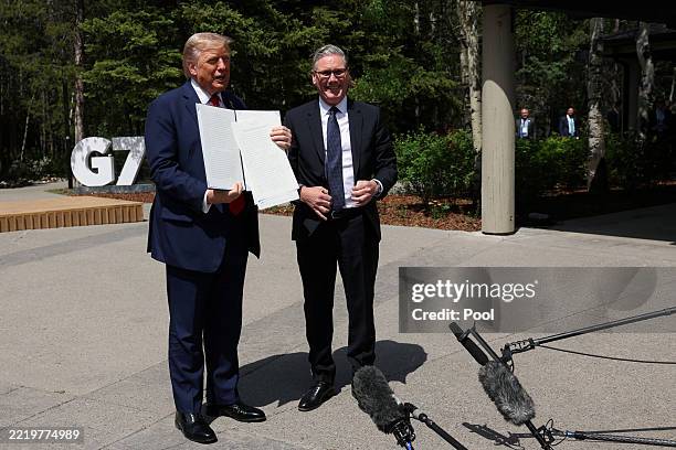 President Donald Trump holds a signed Trade Agreement with Britain during a meeting with British Prime Minister Keir Starmer, at the G7 Leaders'...