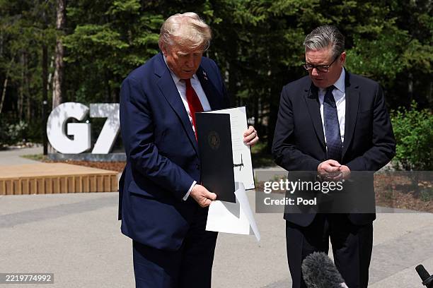 President Donald Trump holds a signed Trade Agreement with Britain during a meeting with British Prime Minister Keir Starmer, at the G7 Leaders'...