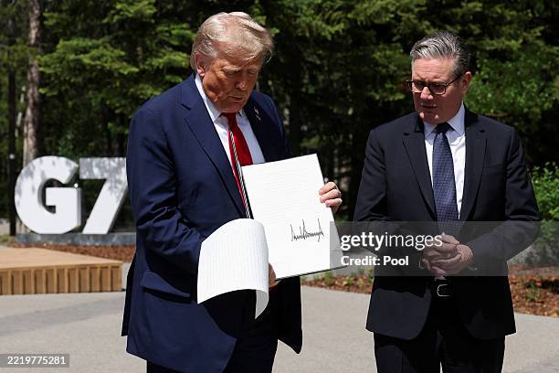 President Donald Trump holds a signed Trade Agreement with Britain during a meeting with British Prime Minister Keir Starmer, at the G7 Leaders'...
