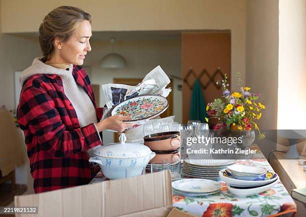 moving house: woman unpacking dishes - fine china plate stock pictures, royalty-free photos & images