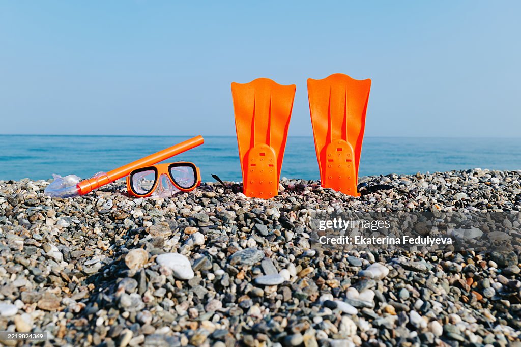Snorkeling mask, tube and fins on sea shore