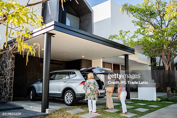 senior women arriving on house and unloading car trunk at house yard - garage driveway stock pictures, royalty-free photos & images