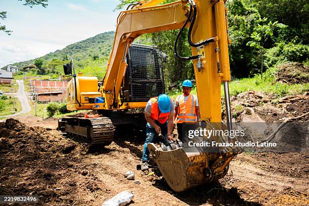 construction workers inspecting excavator bucket at site outdoors - grävmaskin bildbanksfoton och bilder
