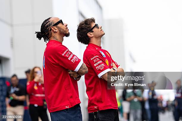 Lewis Hamilton of Great Britain and Ferrari looks on in the paddock with Charles Leclerc of Monaco and Ferrari during previews ahead of the F1 Grand...
