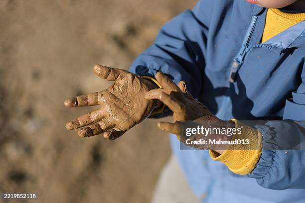 little boy playing with mud in muddy water - mud flat stock pictures, royalty-free photos & images
