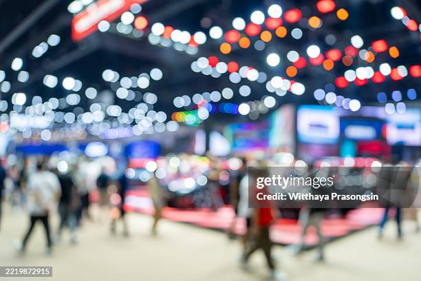 visitors walking in a blurred car showroom at a motor show - messen stock-fotos und bilder